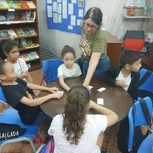 Voluntária conduz atividade lúdica com crianças na Biblioteca Escolar Municipal de Copacabana, Rio de Janeiro.